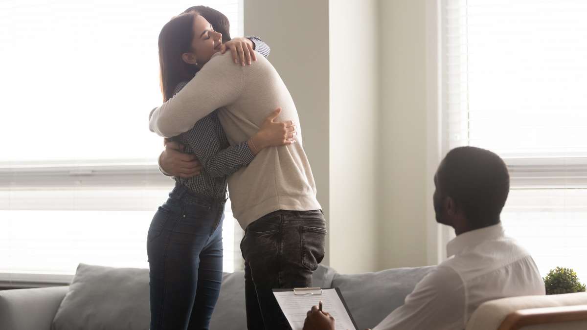 Happy couple hugging in a detox center living room during a counseling session, part of alcohol detox in Nashville.